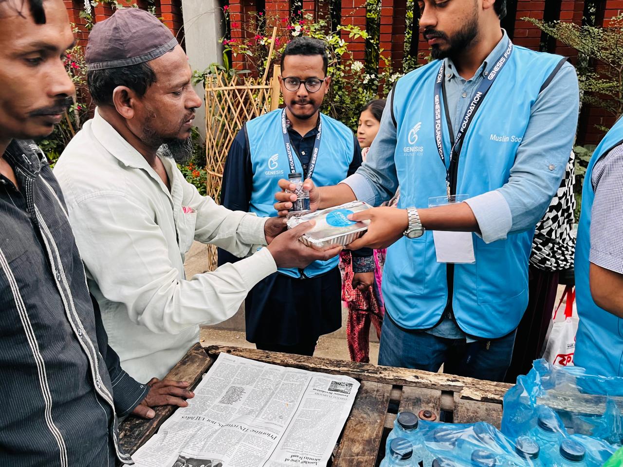 Volunteer handing a meal to a man in Bangladesh